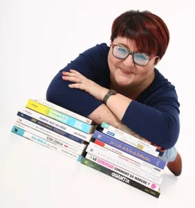 Solange Desabaye – coach posée sur une pile de livres, regard complice et posture ancrée